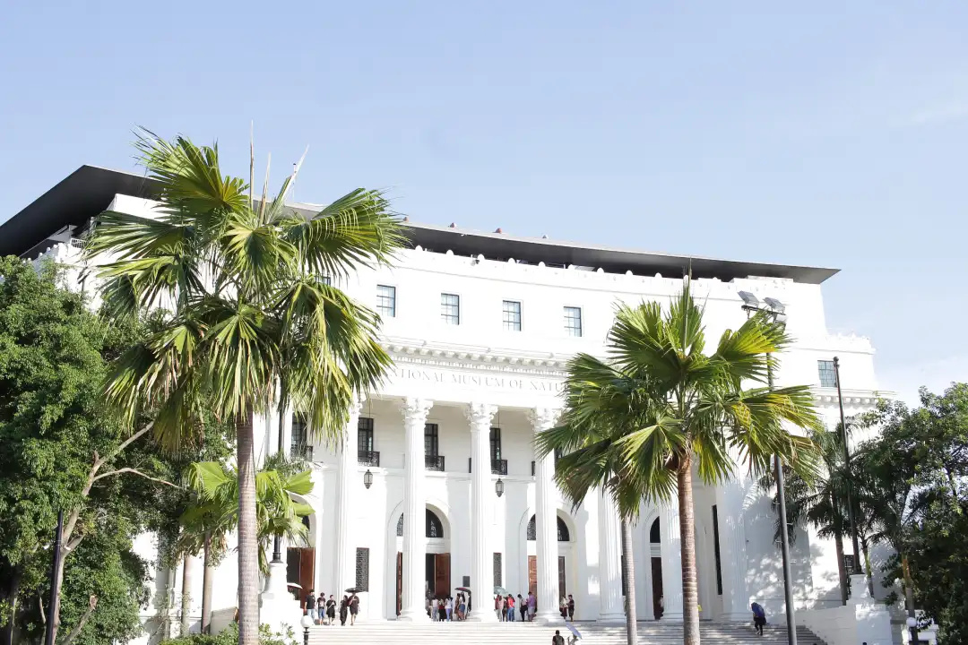 Palm trees framing the entrance of the National Museum of Natural History with visitors in Manila