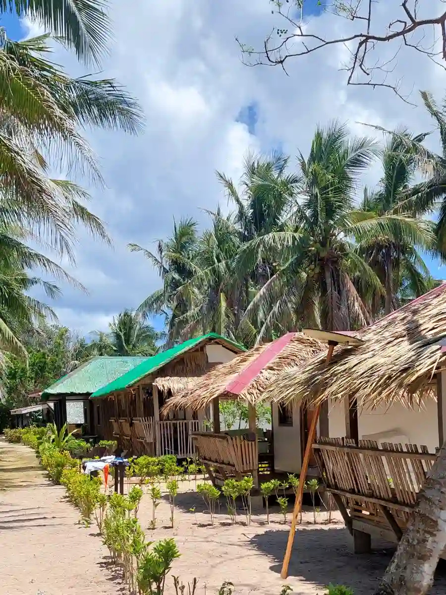 Row of thatched roof nipa hut cottages at La Sable accommodation in Jomalig Island