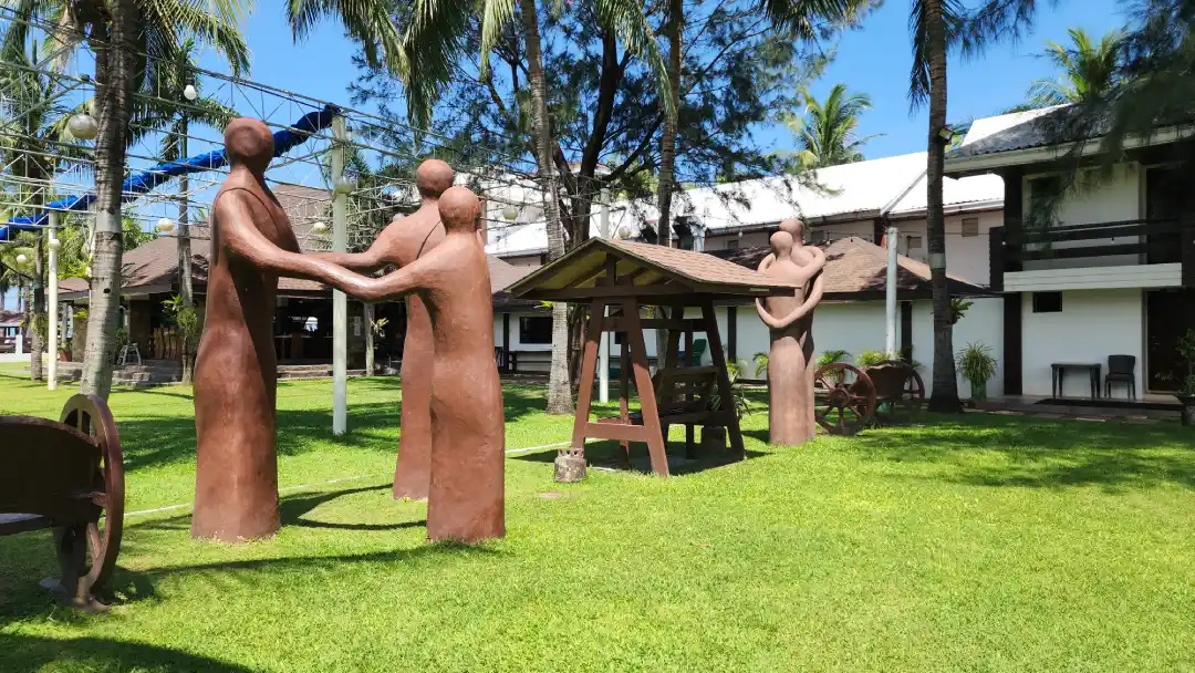 Clay figure sculptures and a wooden swing on the lawn at Bataan White Corals in Morong Bataan