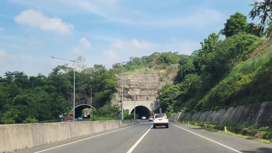 View of twin mountain tunnels along the expressway leading to Morong Bataan, with cars approaching the entrances