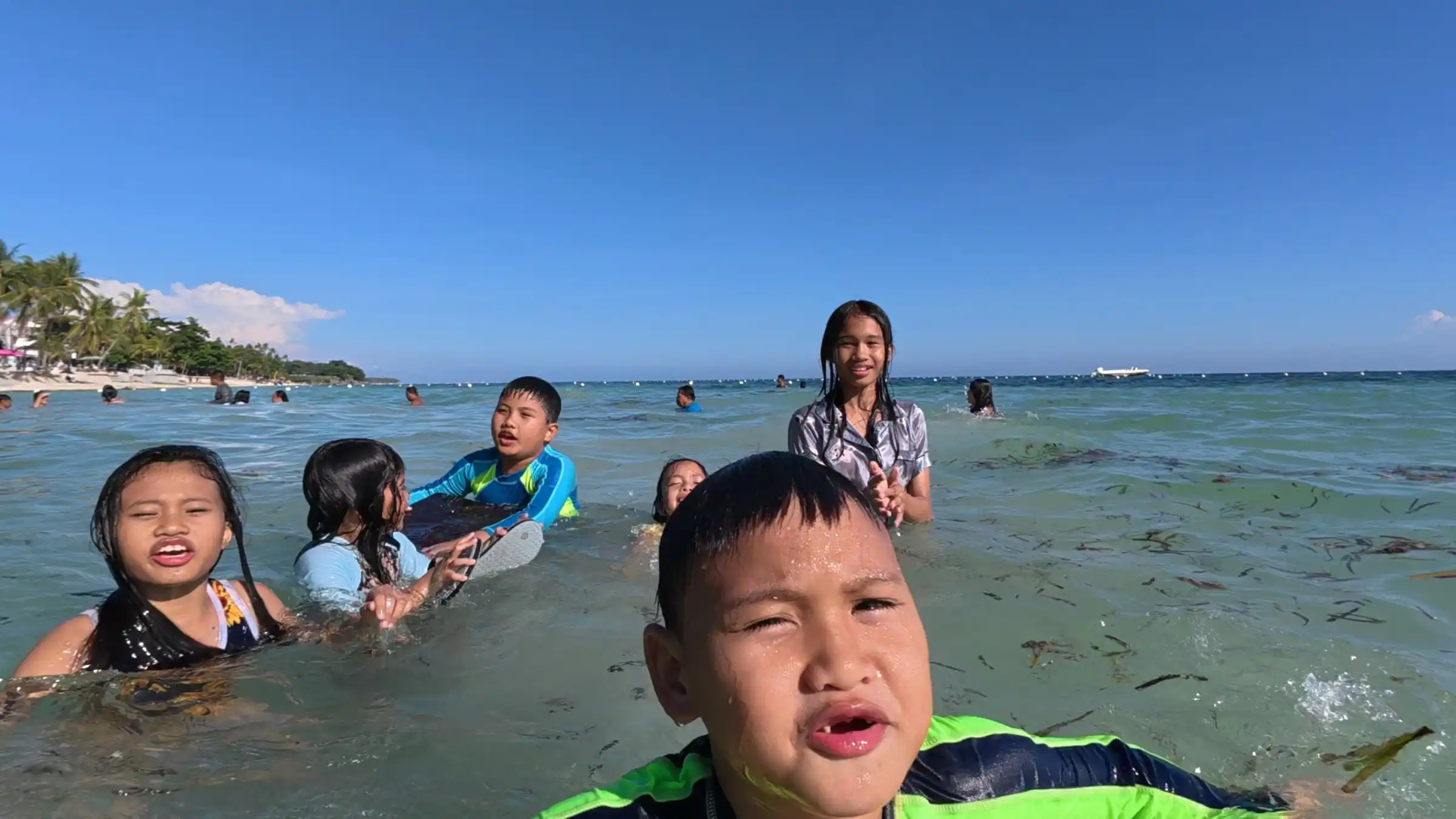 Group of children posing together in shallow water at Kalipayan Beach Panglao Island Bohol
