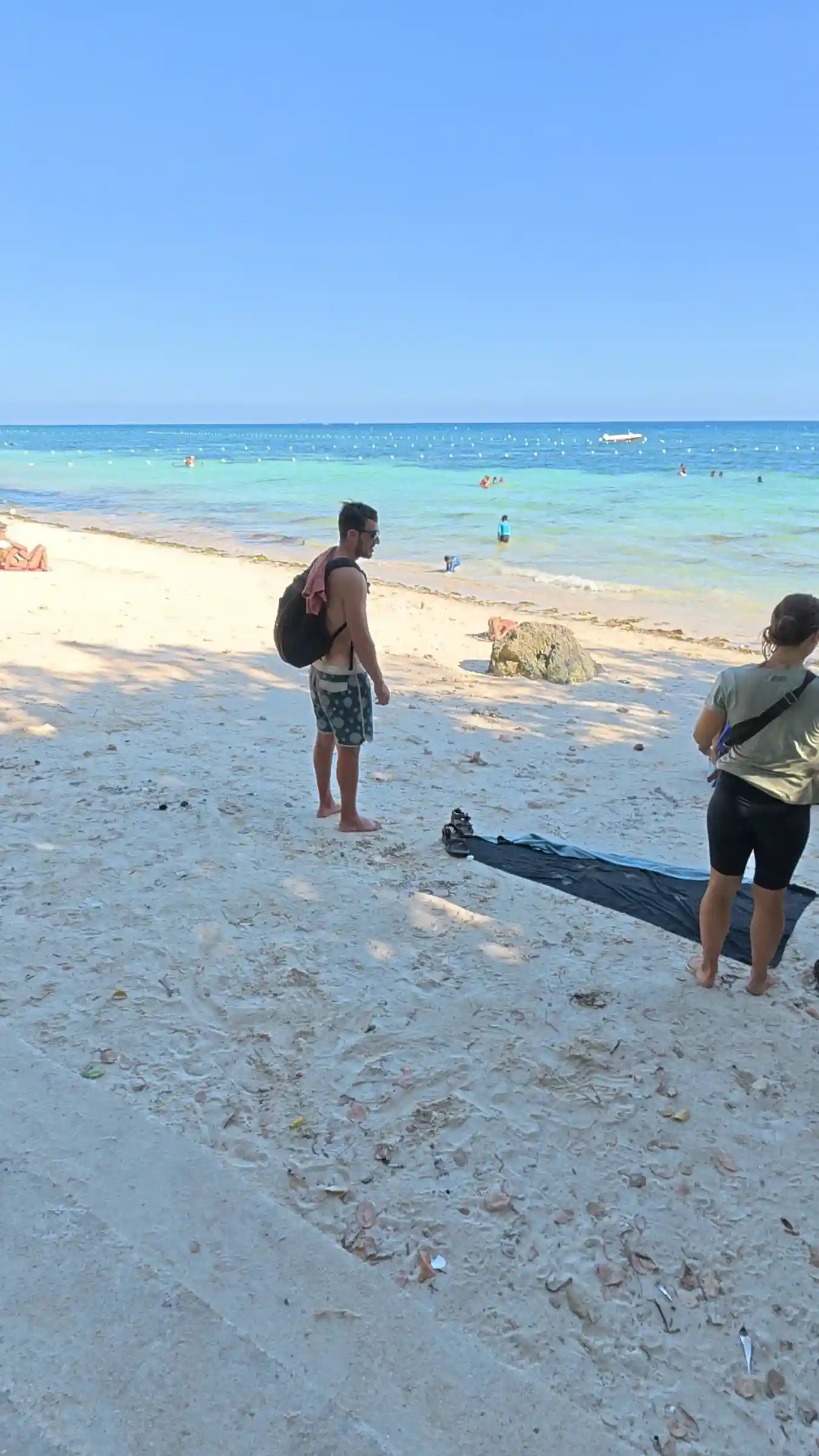 Rock formation shading the sand at Kalipayan Beach with boats and beachfront houses in Panglao Bohol