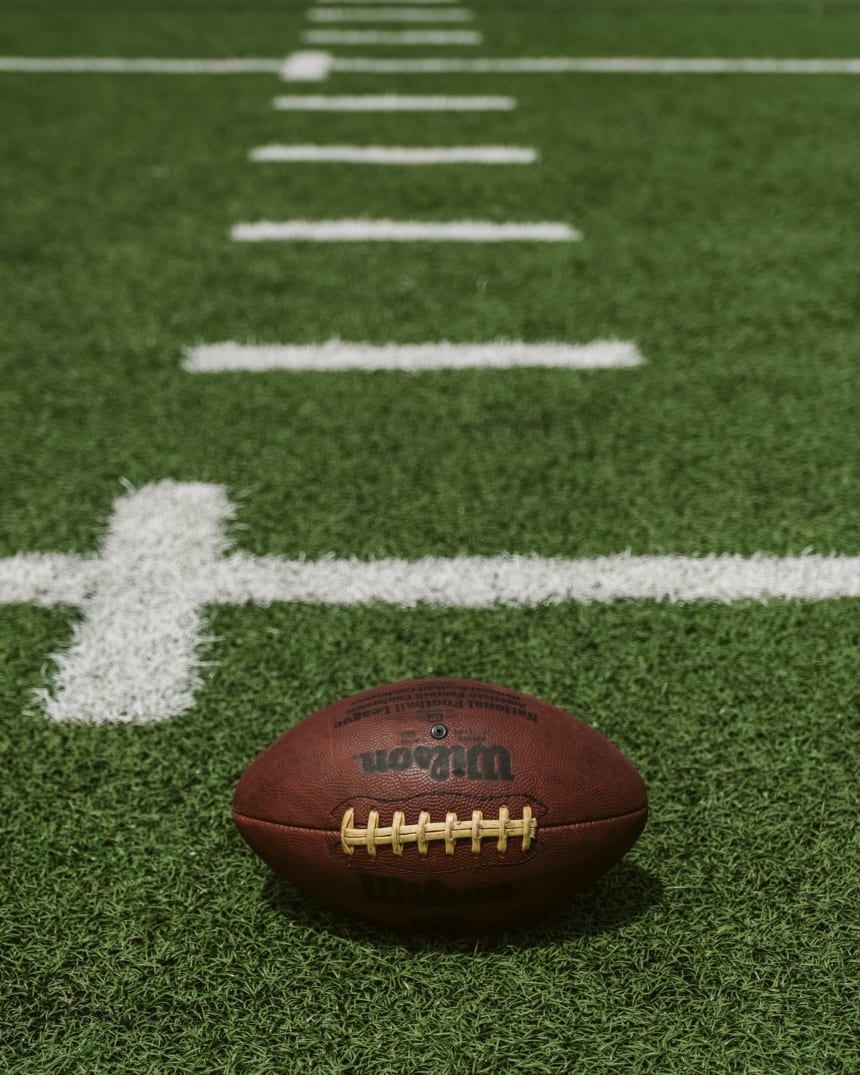 Brown Wilson American football lying on a grass field