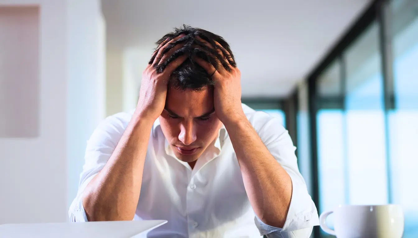 Expat holding their head, feeling overwhelmed with homesickness.