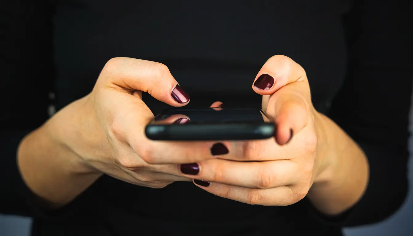 A woman typing, sending a good morning or good night text as part of a daily ritual in a long-distance relationship.