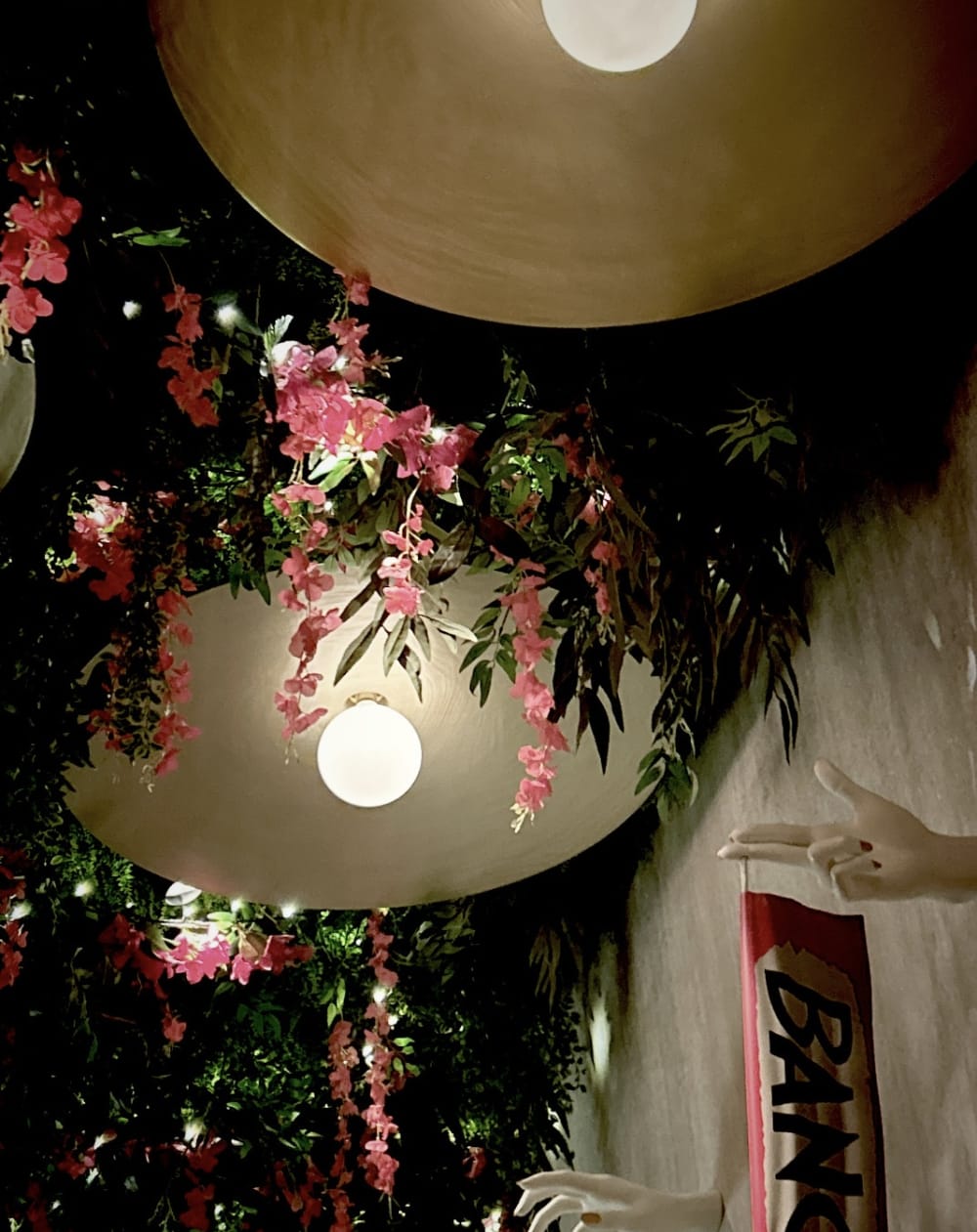 Pink flowers and green leaves dangling from a ceiling