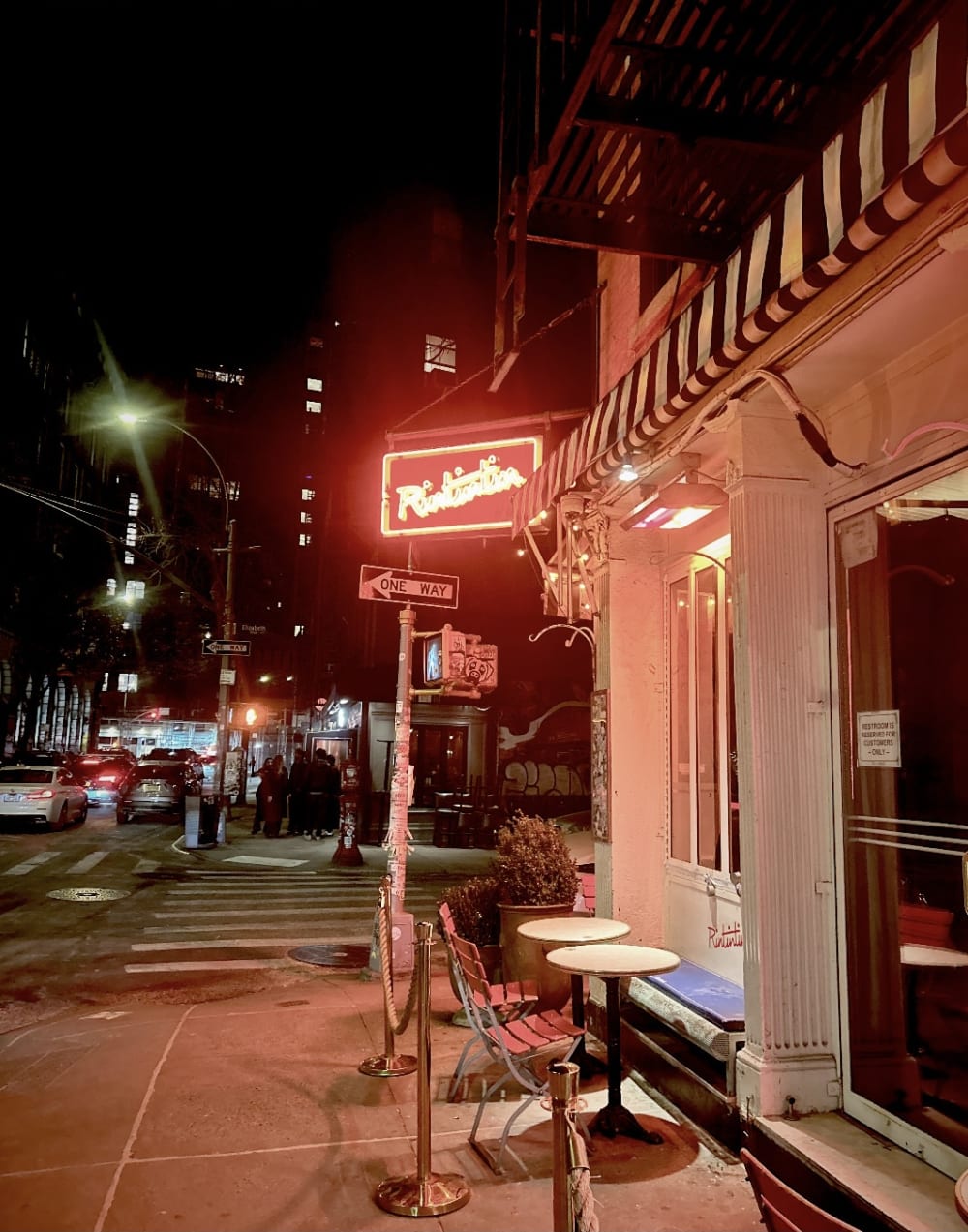 A diner on the corner of a New York City street at night.