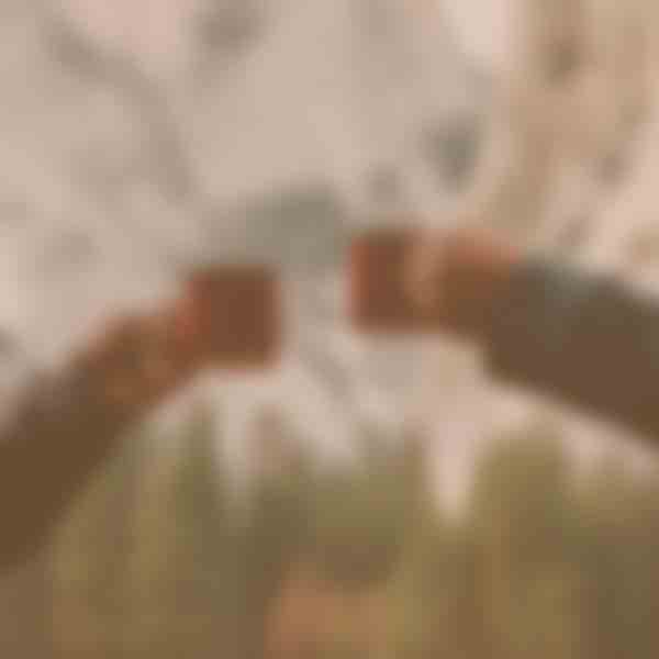 Two people's arms holding up their mugs in a cheers pose