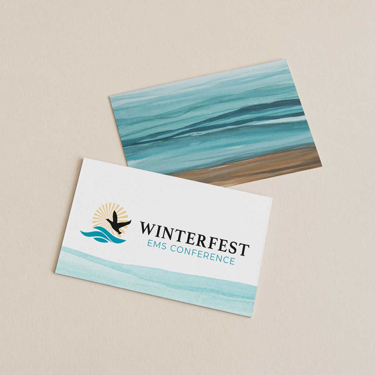 Two cards; the front card has the logo for Winterfest on it with watercolor waves underneath. The back card has the ocean painted with watercolors