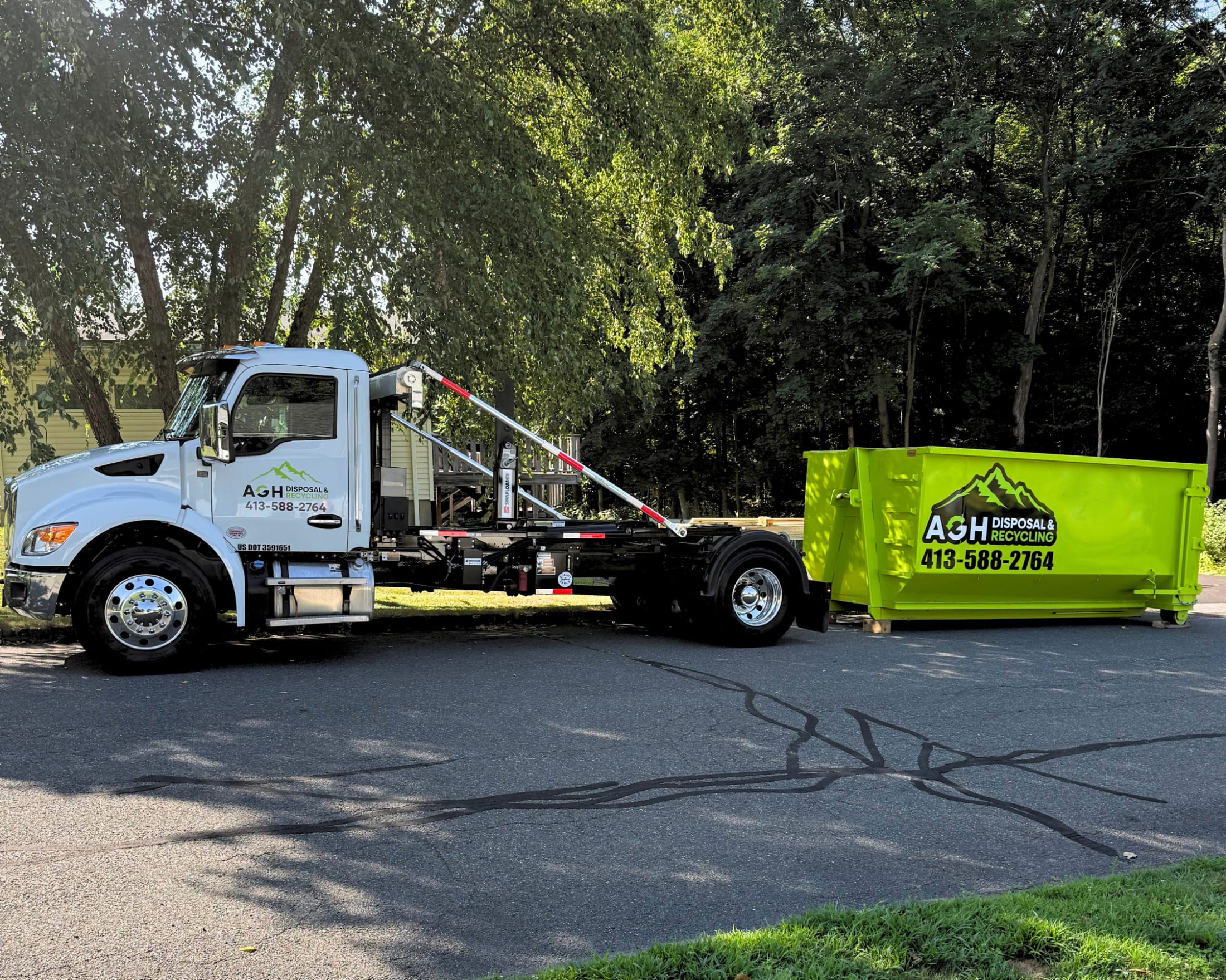 AGH Disposal truck delivering a green roll-off dumpster