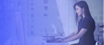 A female recruiter sitting at a desk working behind a laptop