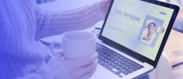 A person sitting and holding a cup in one hand and a laptop in the other