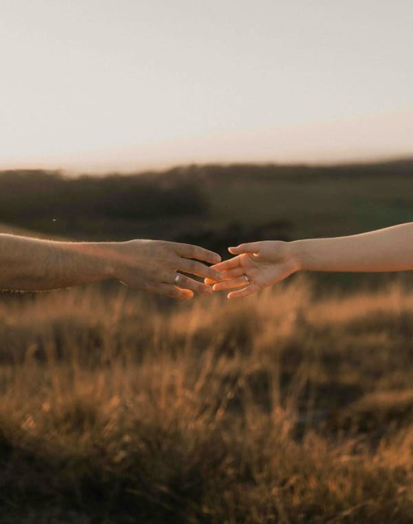 Deux mains qui s'effleurent au coucher du soleil