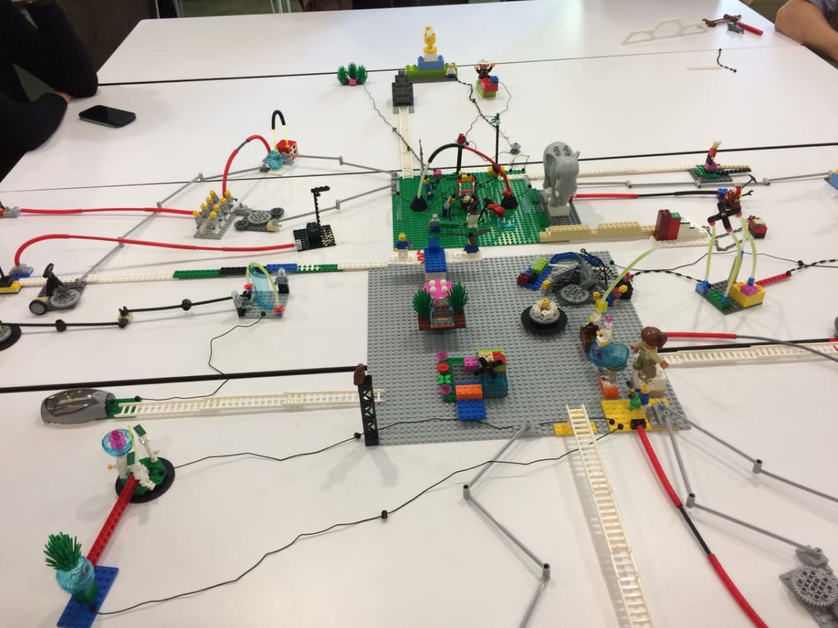 Vue large d'une table d'atelier LEGO Serious Play - les modèles construits par les participants