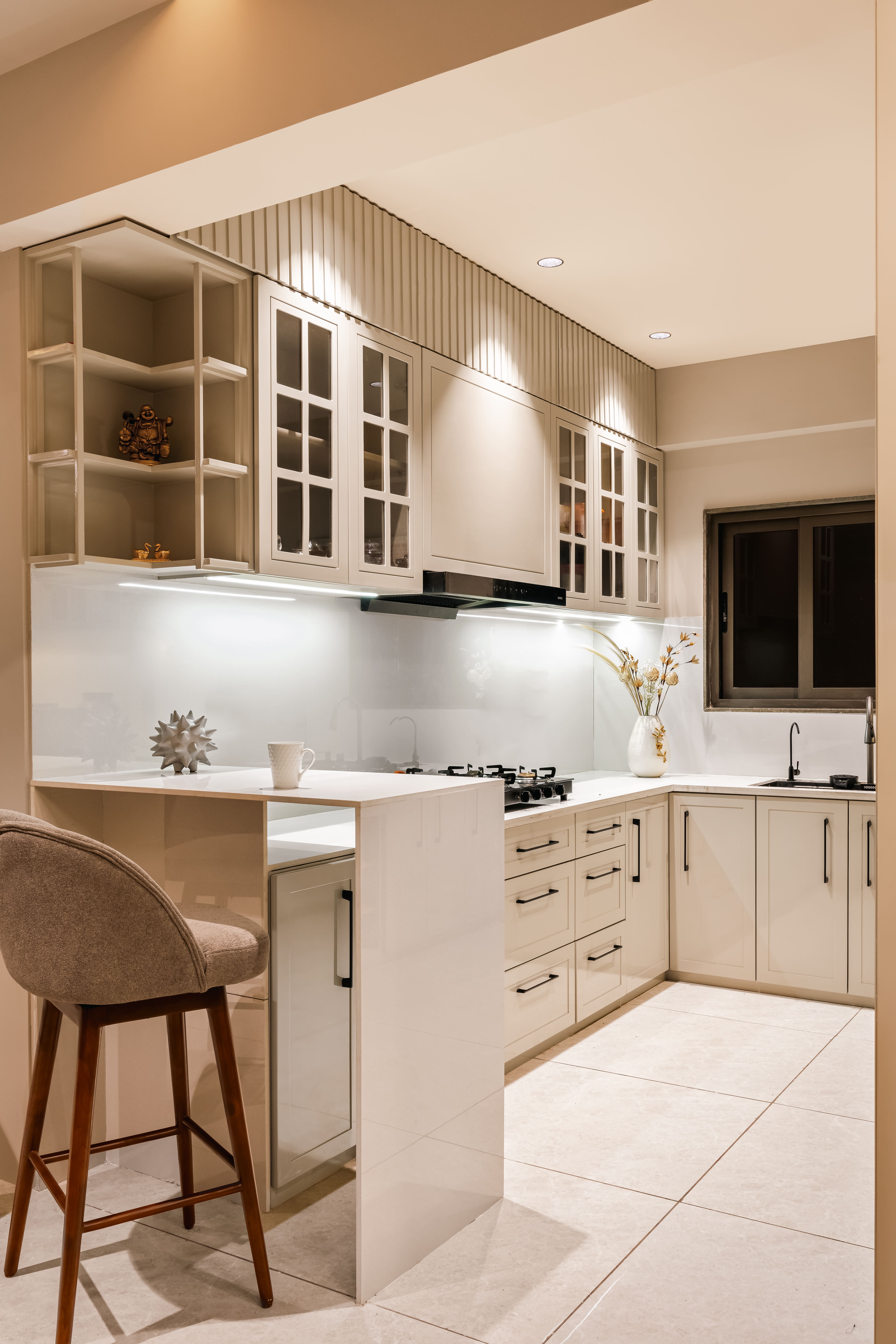 Warm kitchen interior with marble countertops, brass fixtures, and cream cabinetry in soft morning light