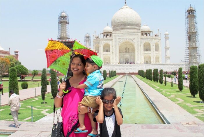 Mulher com sombrinha e crianças na frente do Taj Mahal