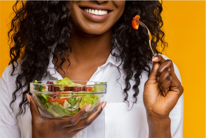 Mulher negra comendo salada