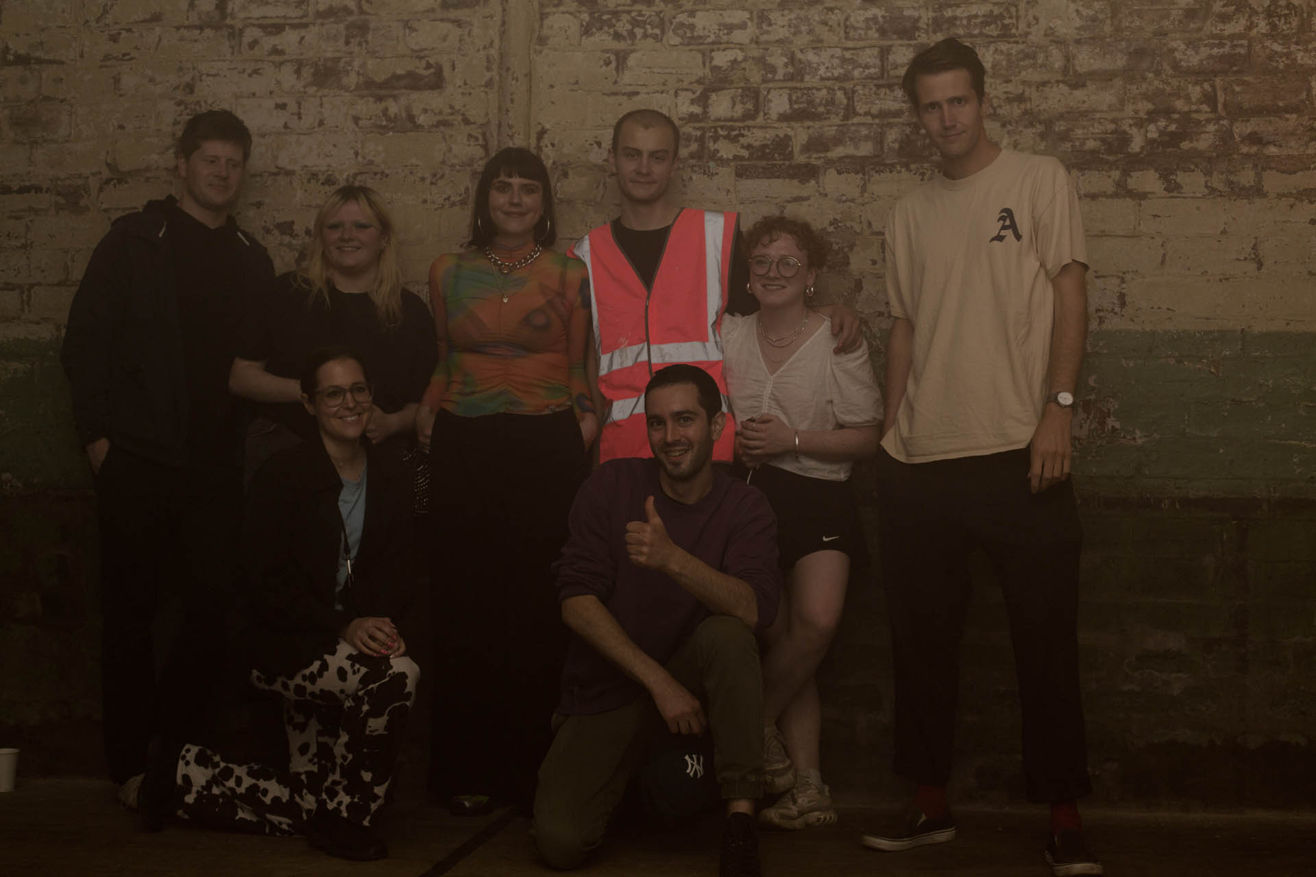 6 people smile for a photo against the wall of the venue