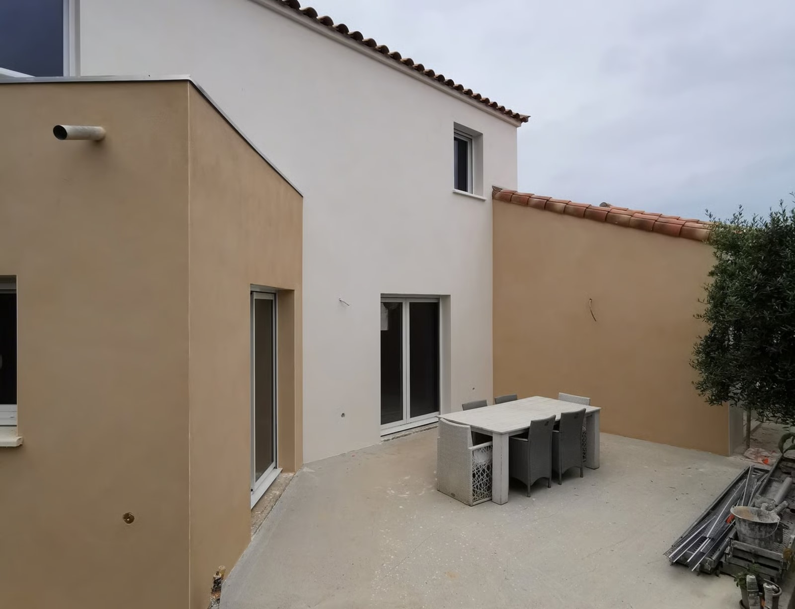 Façade bicolore avec mur en enduit beige et blanc et terrasse extérieure