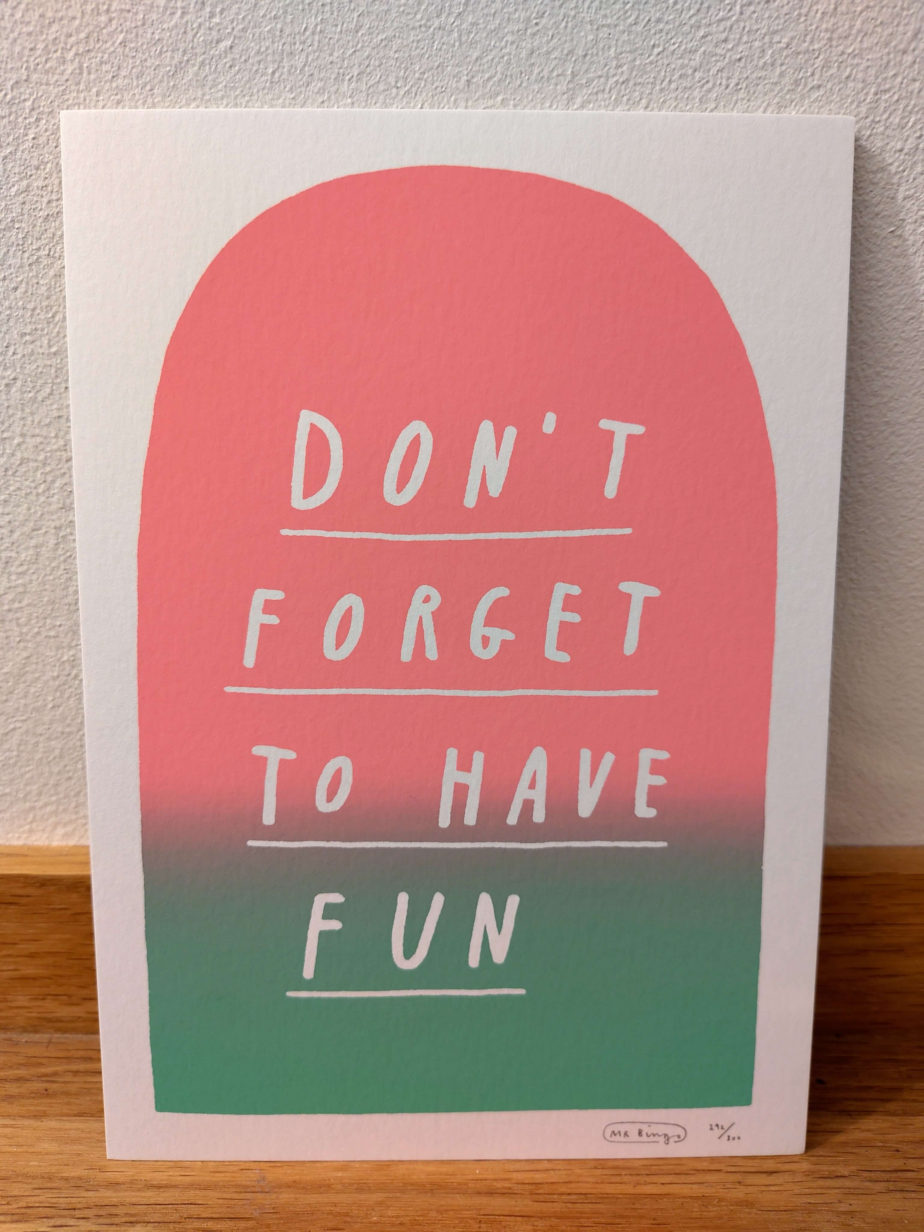 An art print my Mr Bingo. In hand-written, underlined, white capital letters it says "Don't forget to have fun". This is written on a cheerful pink/green gradient coloured tombstone.