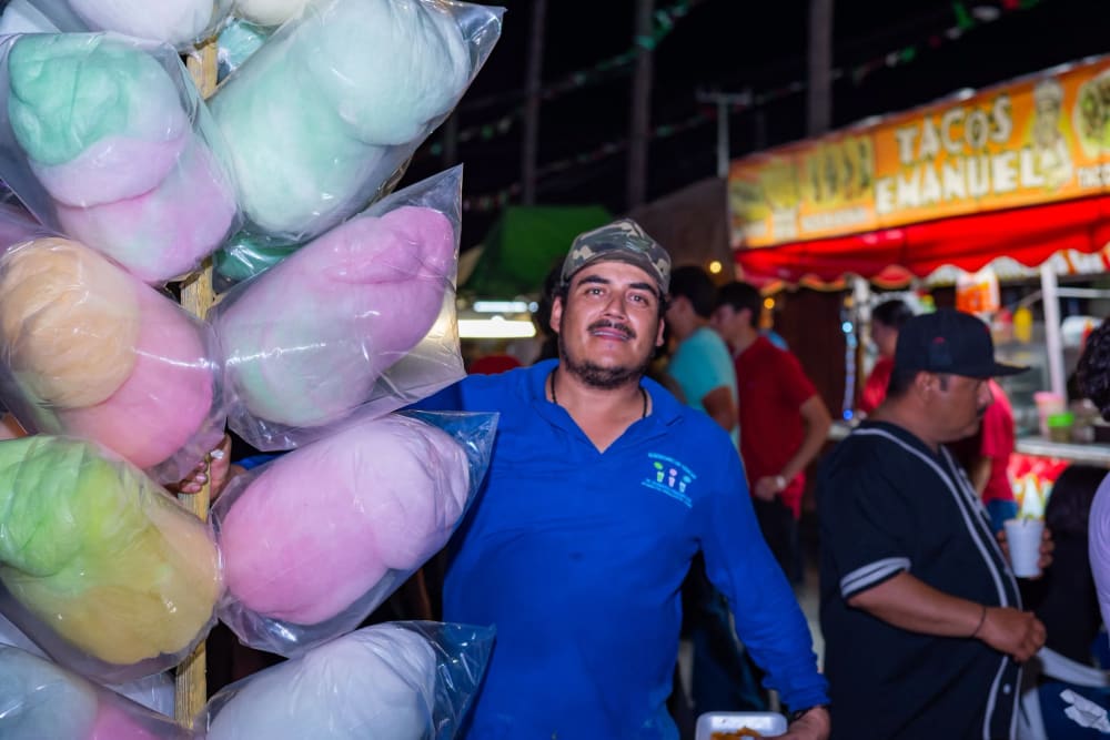 Vendedor de algodones de azúcar en su puesto, con los tacos Emanuel al fondo