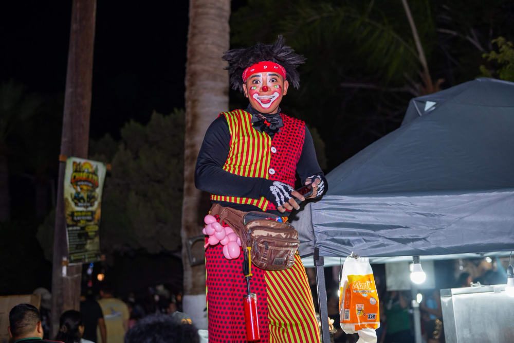 Payaso sobre zancos con vestuario tricolor en la verbena nocturna