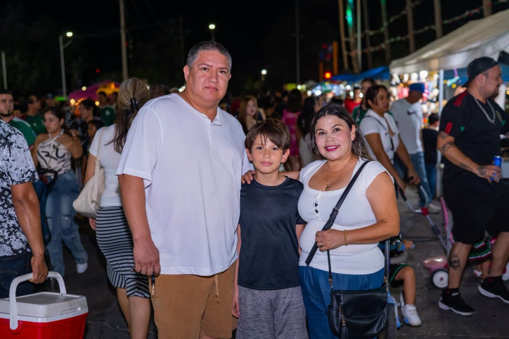 Familia posando sonriente en medio de la verbena popular