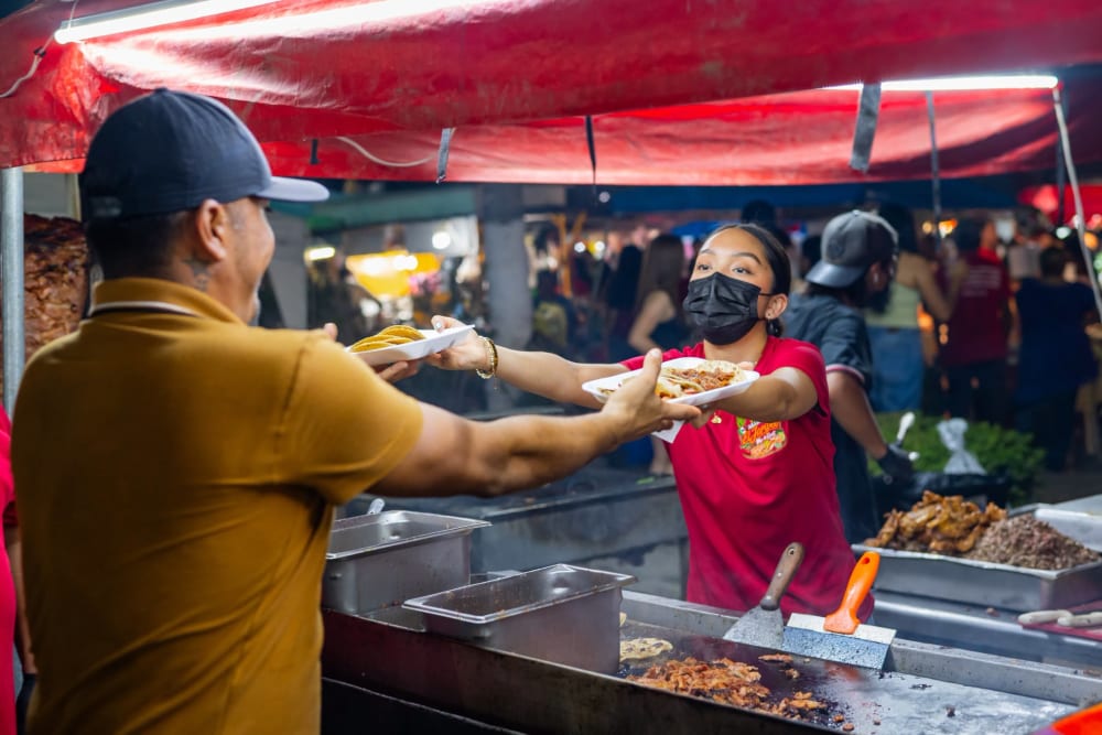 Taquero sirviendo tacos recién preparados en su puesto nocturno