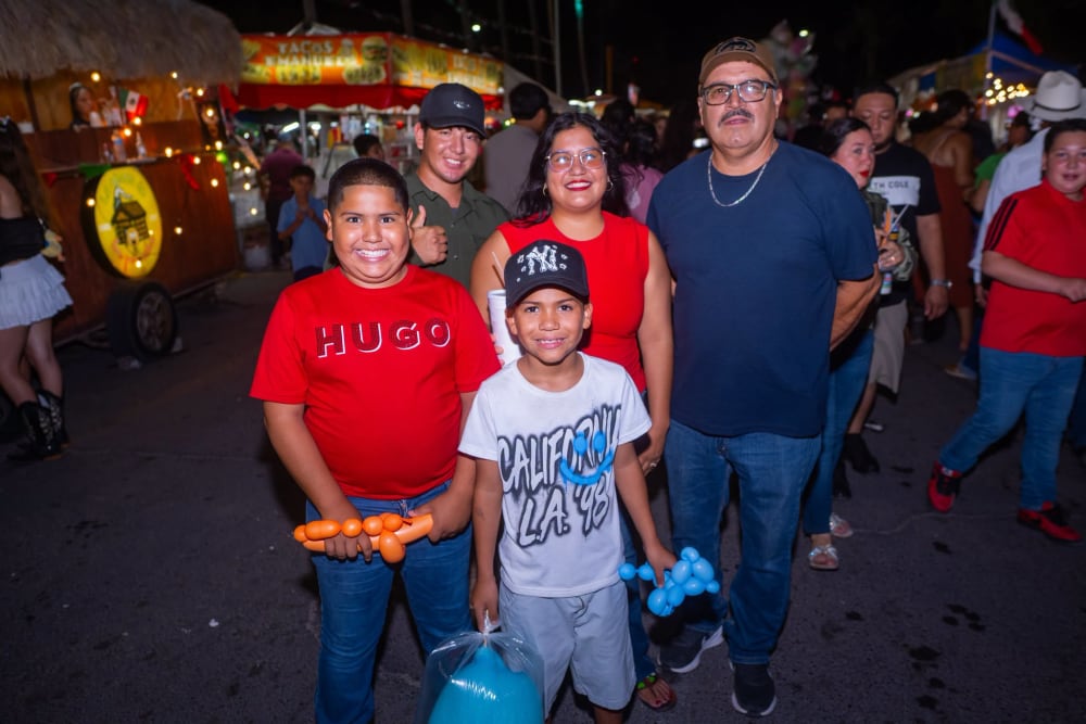 Niños con globos y algodón de azúcar junto a sus familias en la feria nocturna