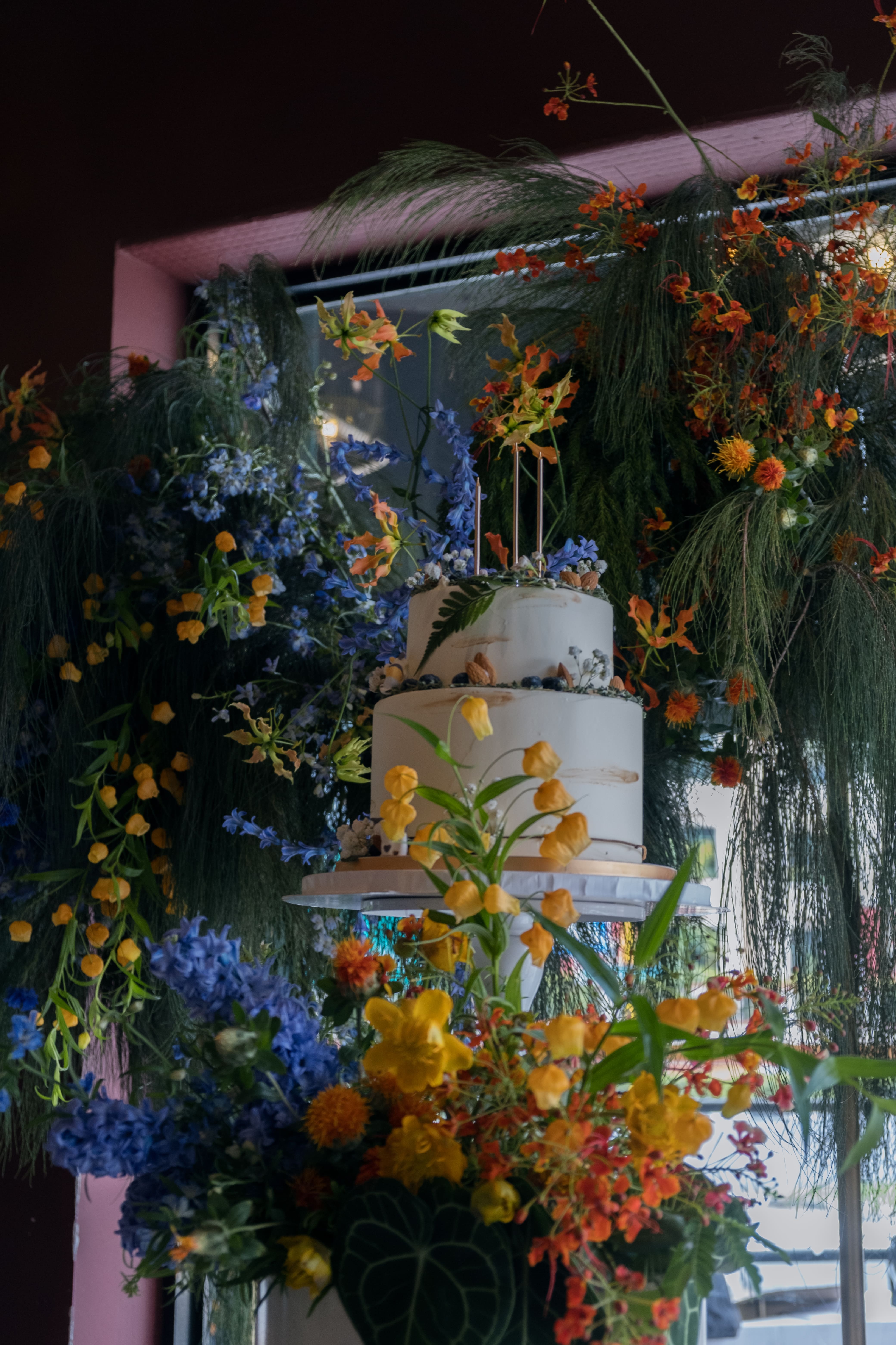 Cake styled with vibrant florals in blue and orange tones.