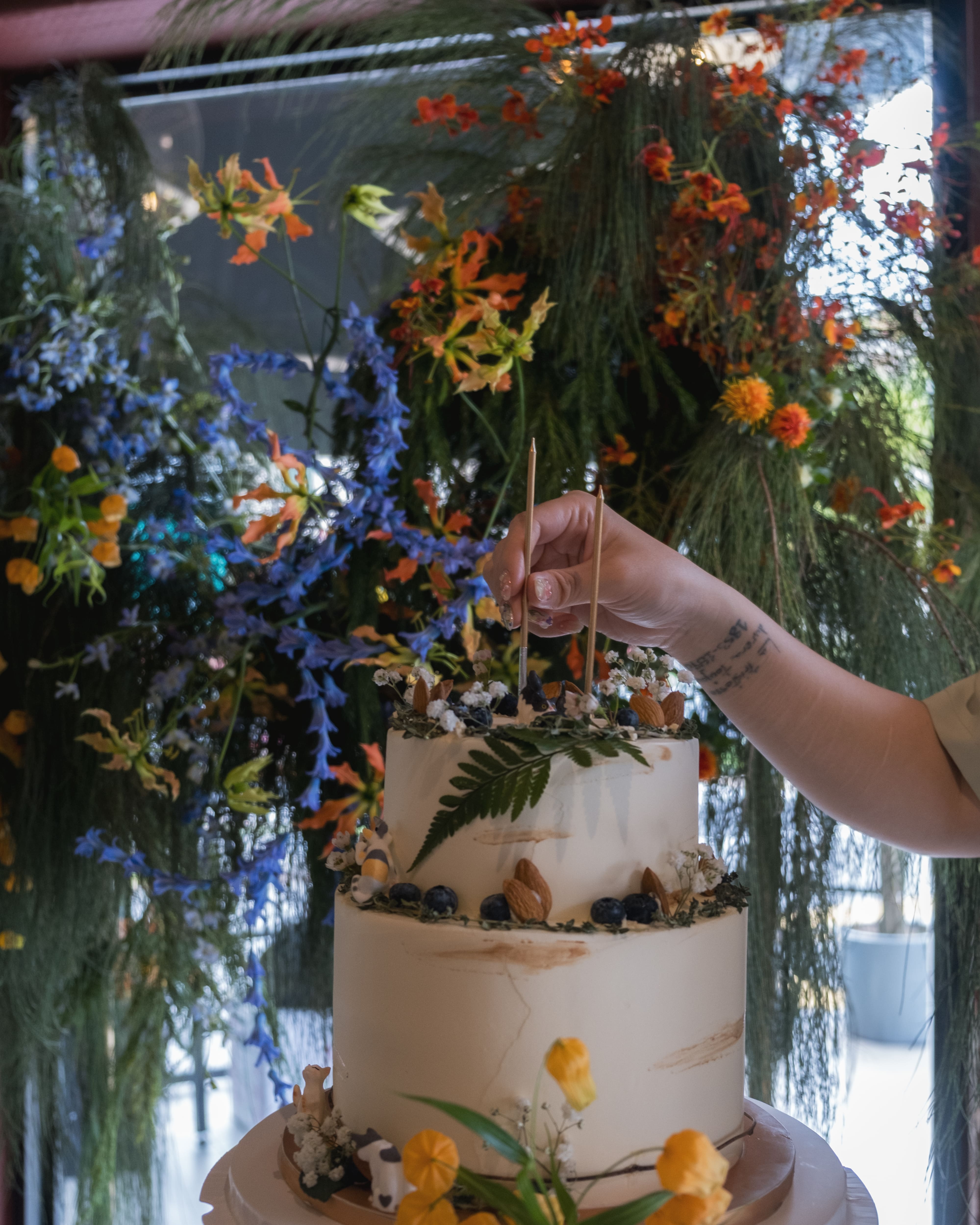 Hand placing candle on a white cake for a birthday party. 
