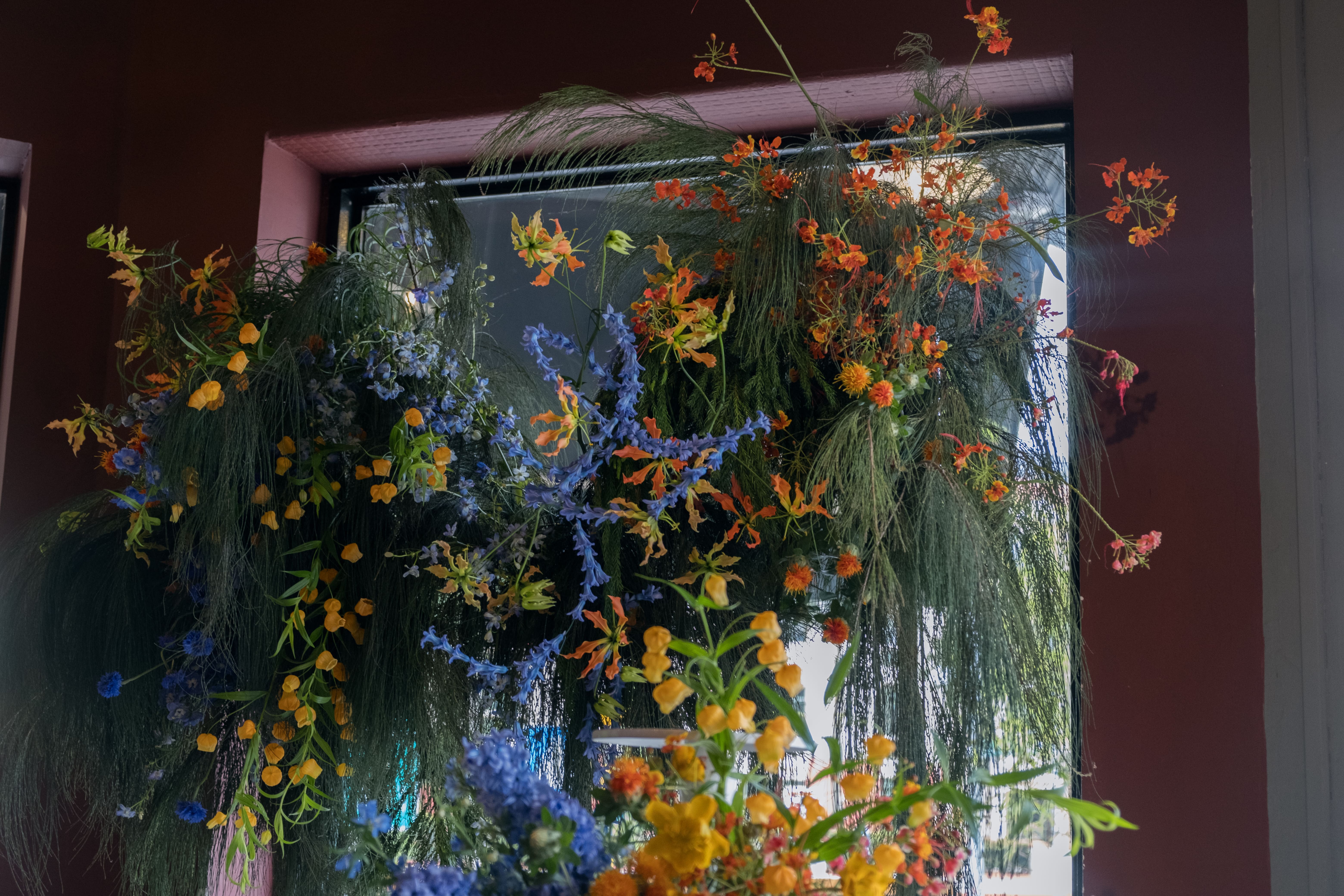 Bold floral frame with arrangements of delphinium, chinese latern lilies, peacock flowers and greenery.