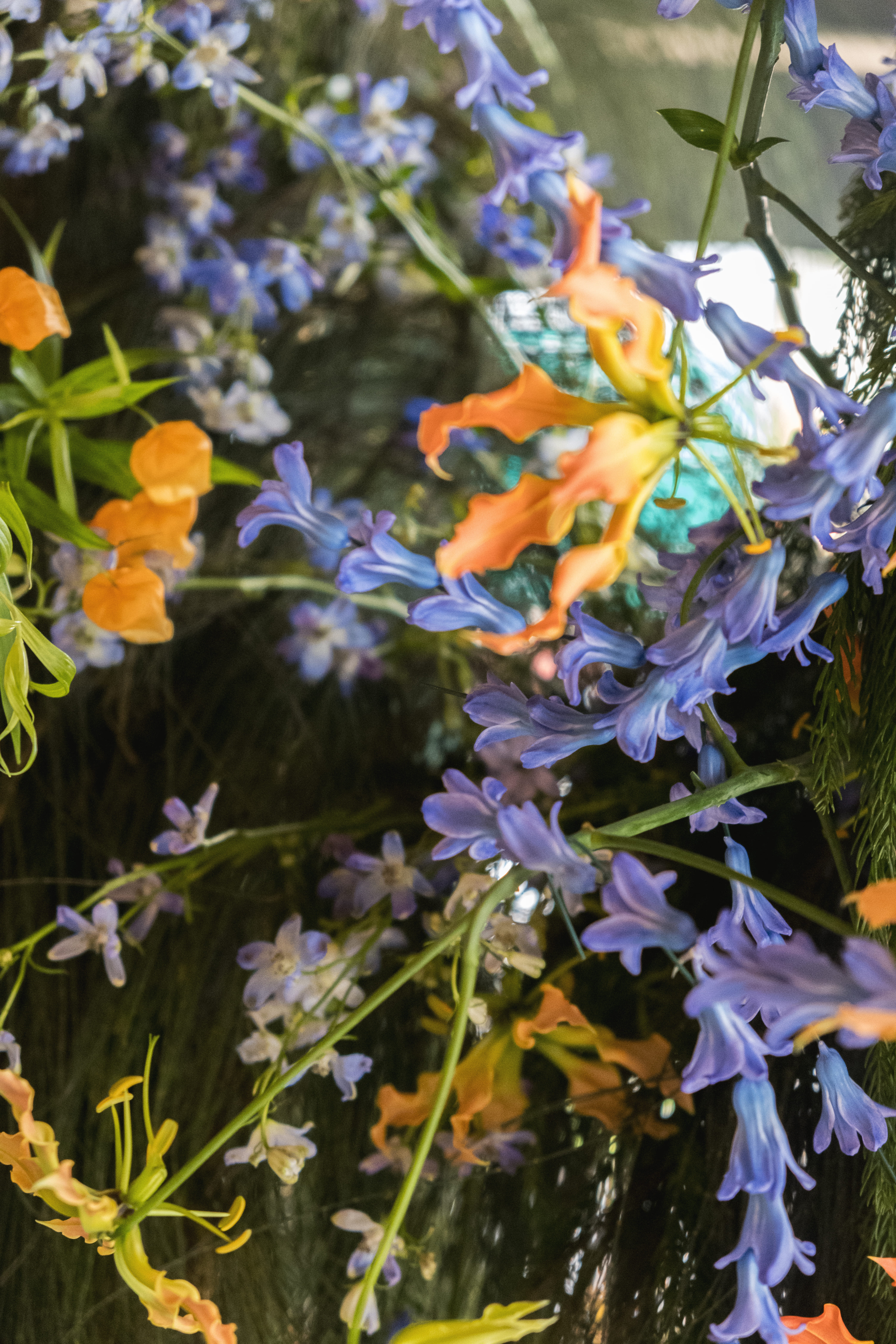 A floral cluster in chinese latern lilies orange and delphinium blue hues.