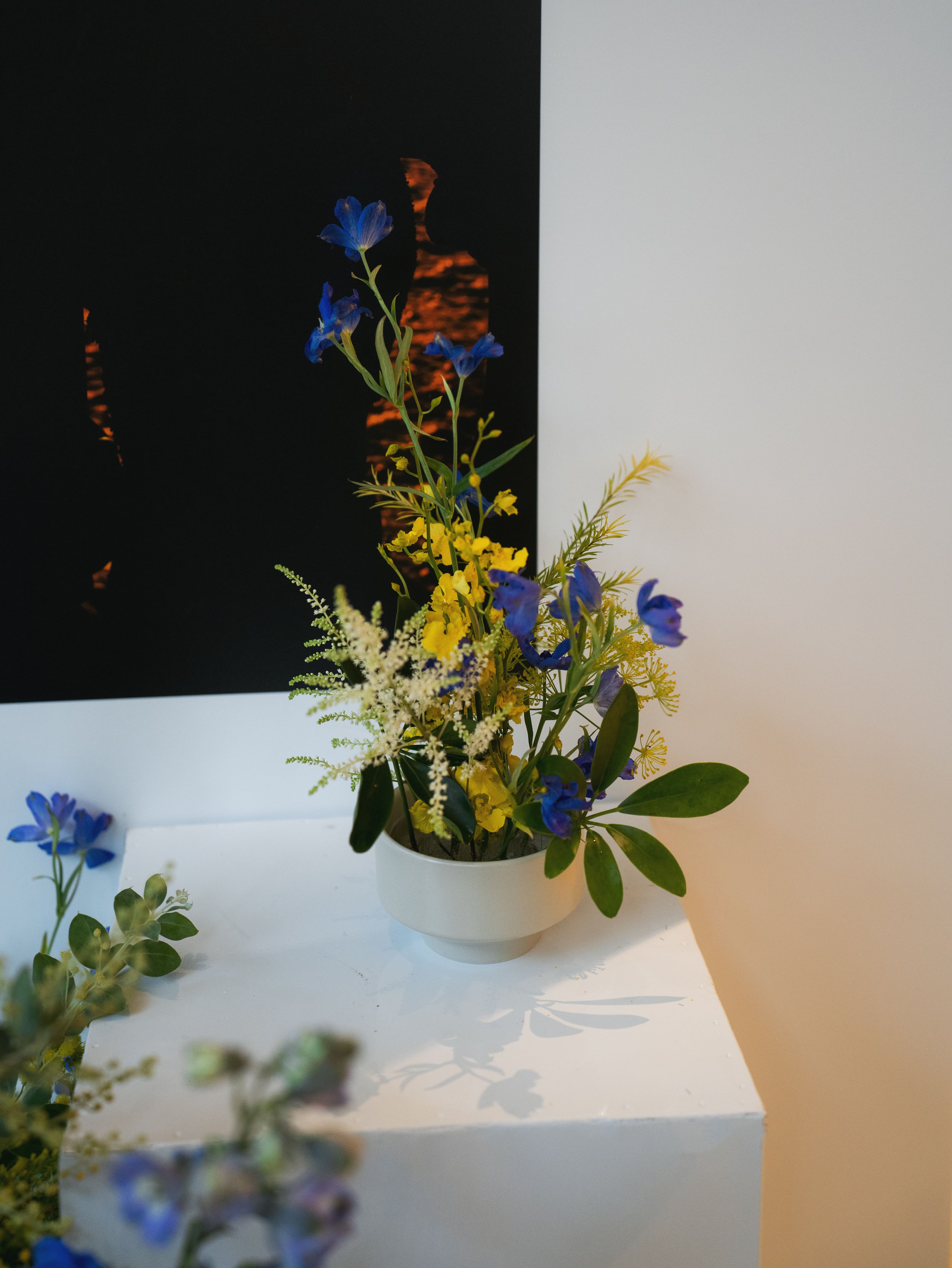 Artistic ikebana-style arrangement with blue and yellow flowers