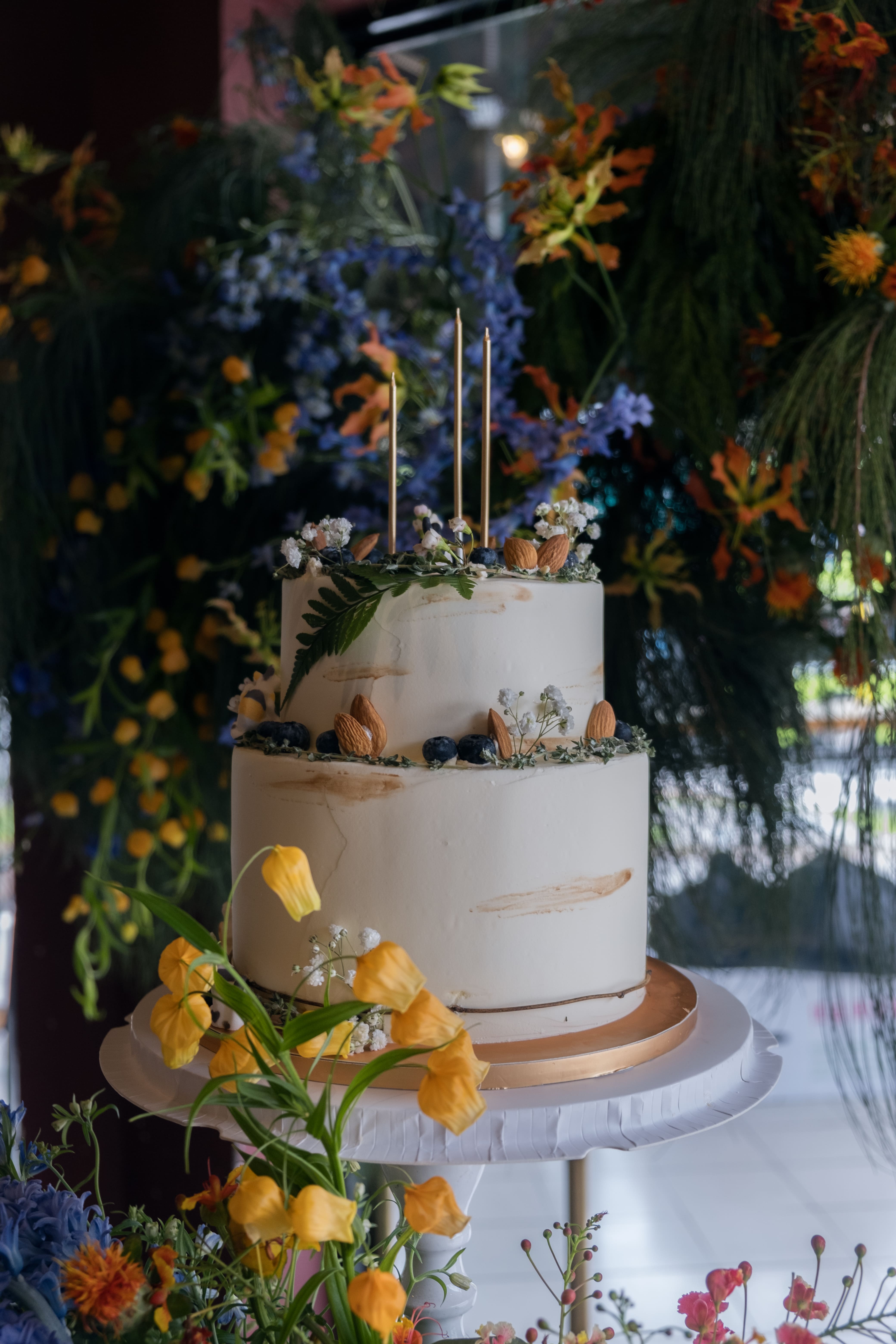 Full shot cake styled with vibrant florals in blue and orange tones.