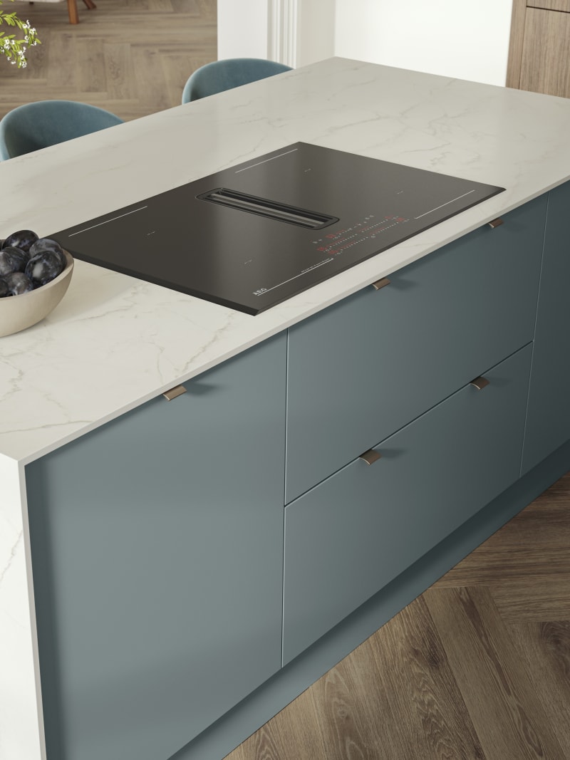 Overhead view of kitchen island with marbled dekton worktop, integrated hob and Soho Duck Blue cabinetry from Magnet.