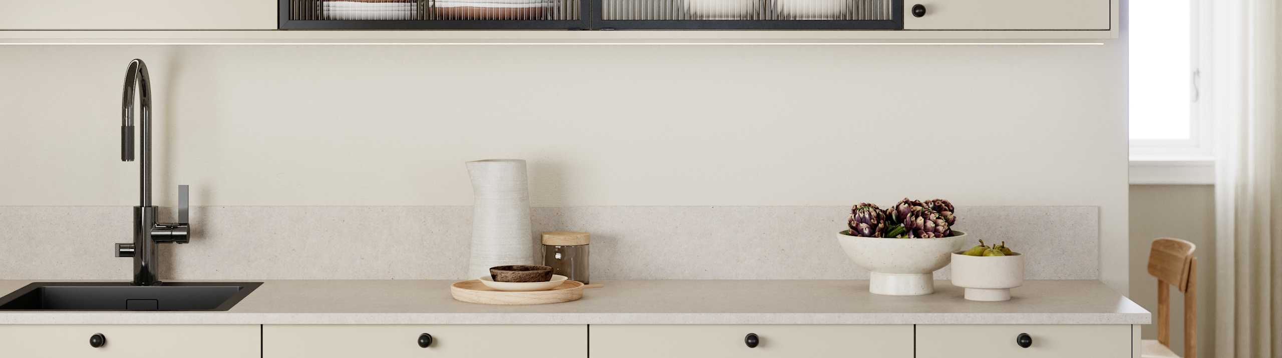Beige melaminkjøkken Vidde Korn med sorte håndtag, sort kran, og vitrinedør med sort aluminiumsramme og rillede glass.