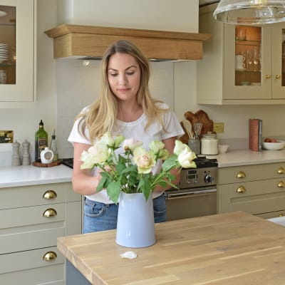 Magnet kitchen customer Leanne placing roses in a case on the kitchen island counter in her country cottage.