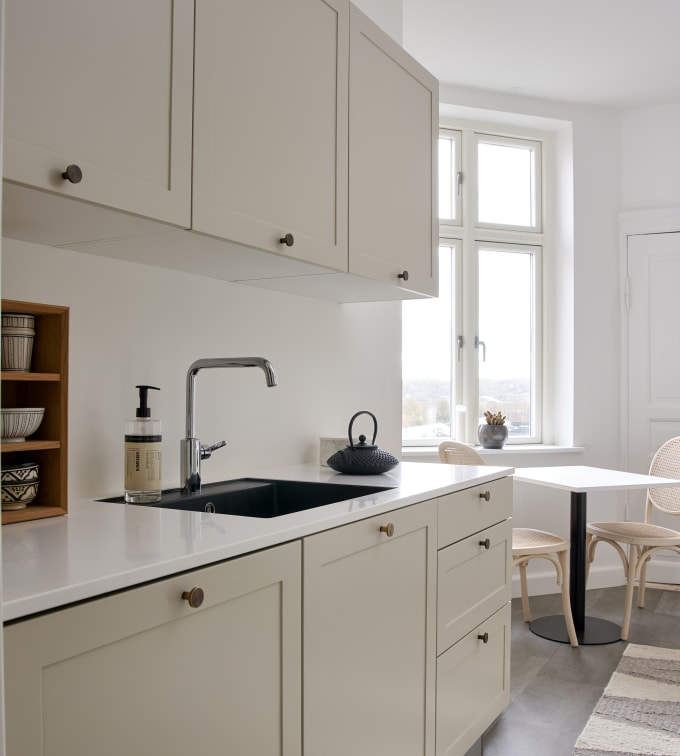 Beige retrokøkken Square Sand køkken fra INVITA med messing håndtag, hvid bordplade