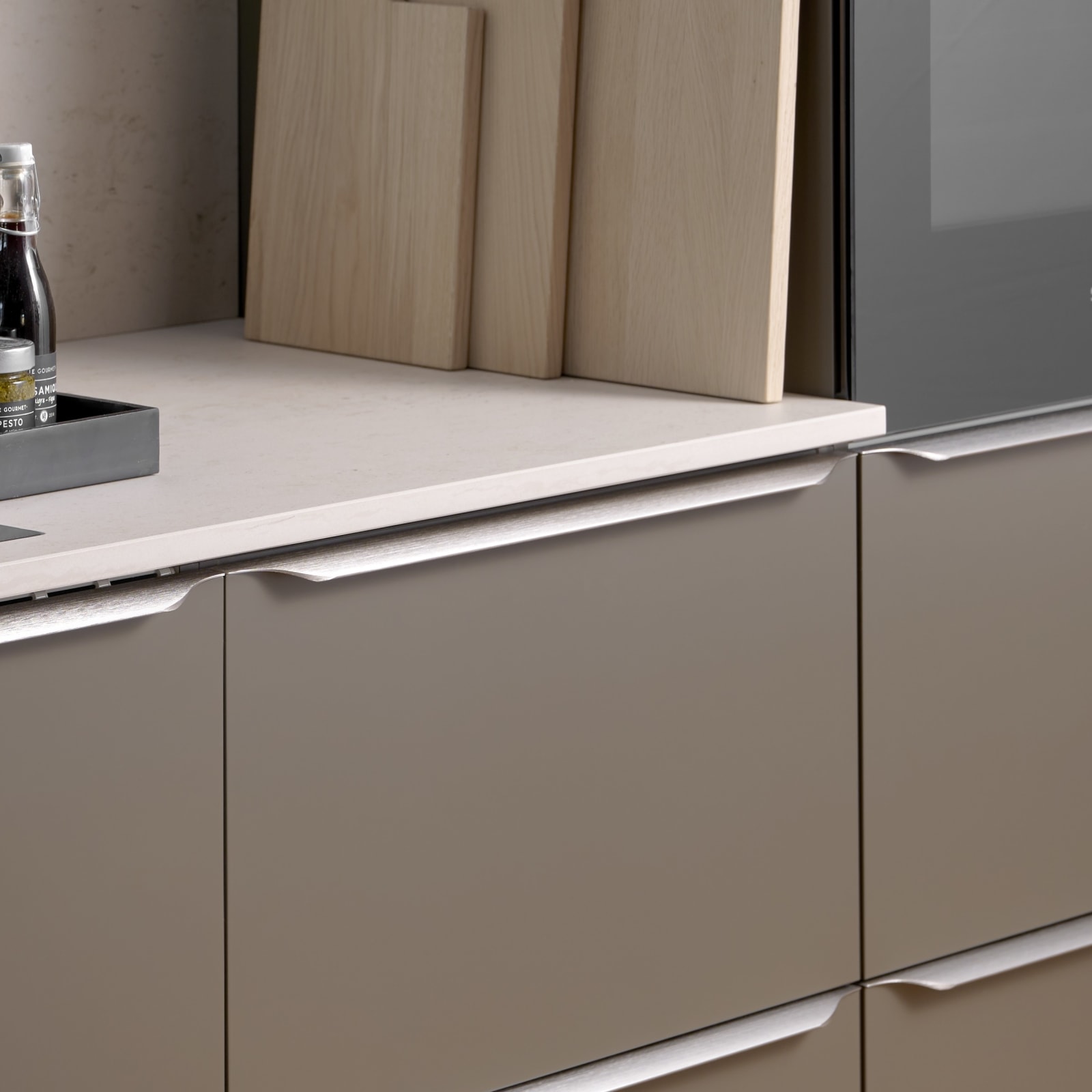 Minimalistisk brun køkken Newline Bark fra INVITA med indbygningsovne i højskabe, diskret greb i stål og lys beige bordplade med matchende splashback