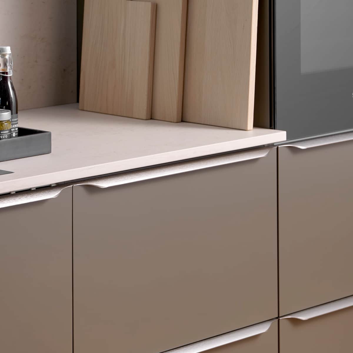 Minimalistisk brun køkken Newline Bark fra INVITA med indbygningsovne i højskabe, diskret greb i stål og lys beige bordplade med matchende splashback