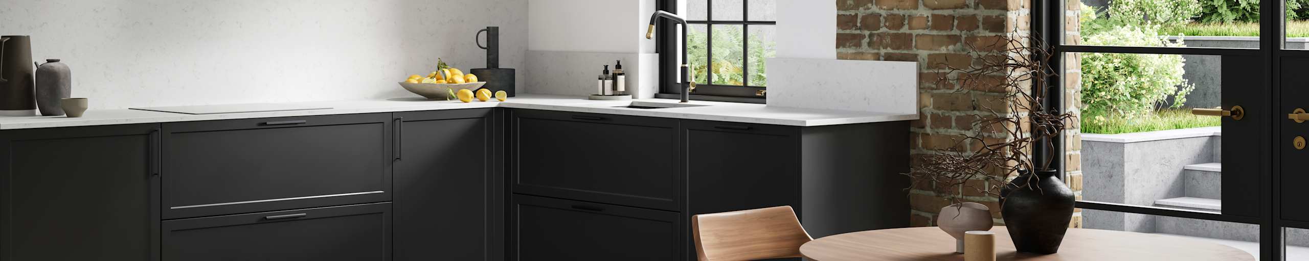 View of modern shaker kitchen Brunswick Sumi Black, with screen extractor over induction hob, black frame skylights with wood dining table and chairs in foreground, combination of white walls and sxposed brick wall.