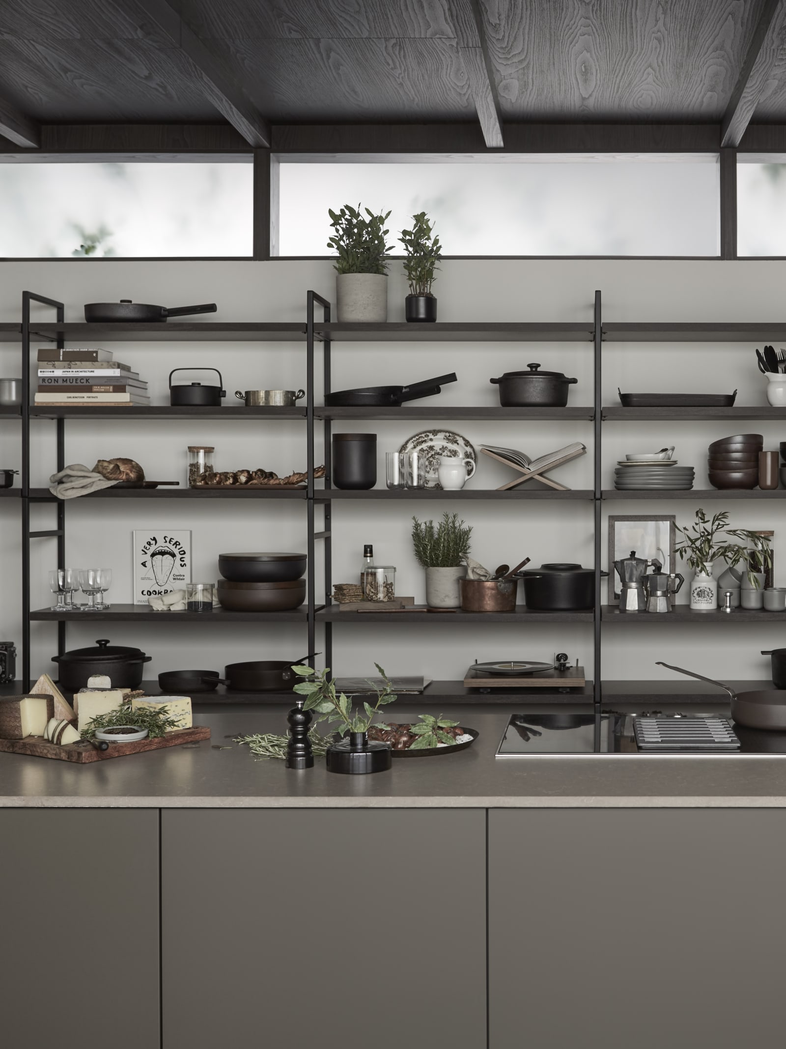 Marbodal Arkitekt plus Bark - kökslucka i målad brun kulör. Köksö med bänkskiva Iron Bark i kvartskomposit, diskho Franke Mythos. Stor vägghylla med ett integrerat skrivbord ger plats att sätta din stil på köket.