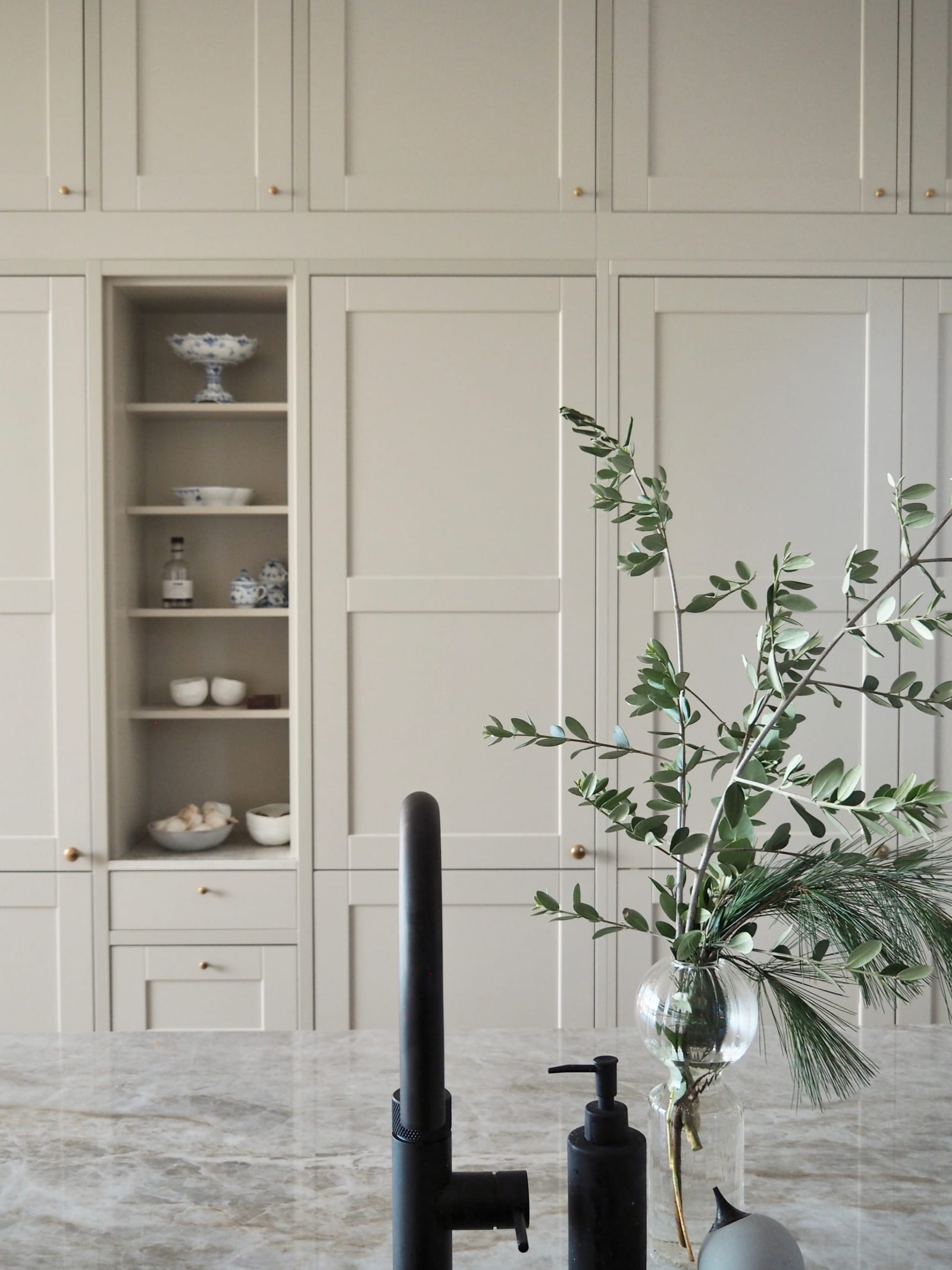 Nærbillede af sort Quooker vandhane i køkkenet med Dekton Taga bordplade og en vase med grønne kviste