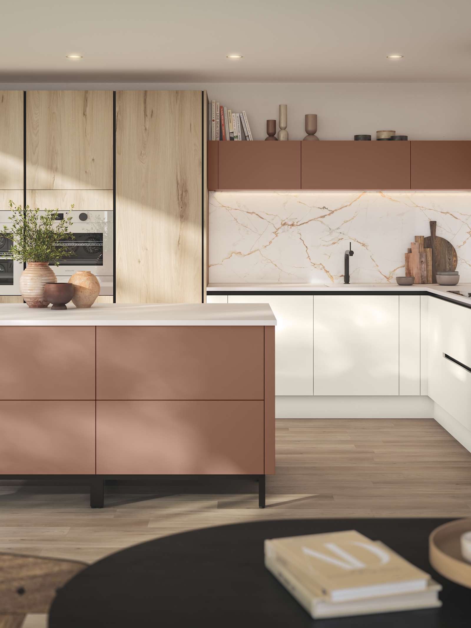 Integra Portobello Bosco as tall cabinets with integrated Samsung Ovens, white handleless Integra Soho cabinetry and a kitchen island in the shade Baked Clay, matching top cabinets and the beautiful fan above hob, all decorated with earth tone ceramics and plants.