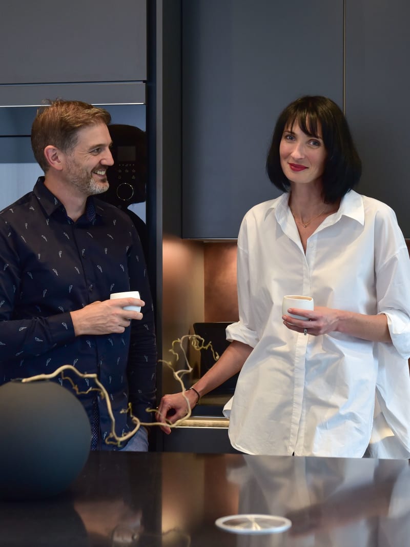 Anna and Andrew each holding a cup of coffee in their dark and decadent handleless Integra Soho Charcoals from Magnet.