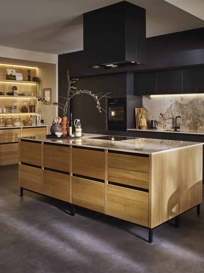 View of natural oak Nordic Craft kitchen island contrasting against the dark Sumi Black Hoxton cabinetry behind it.