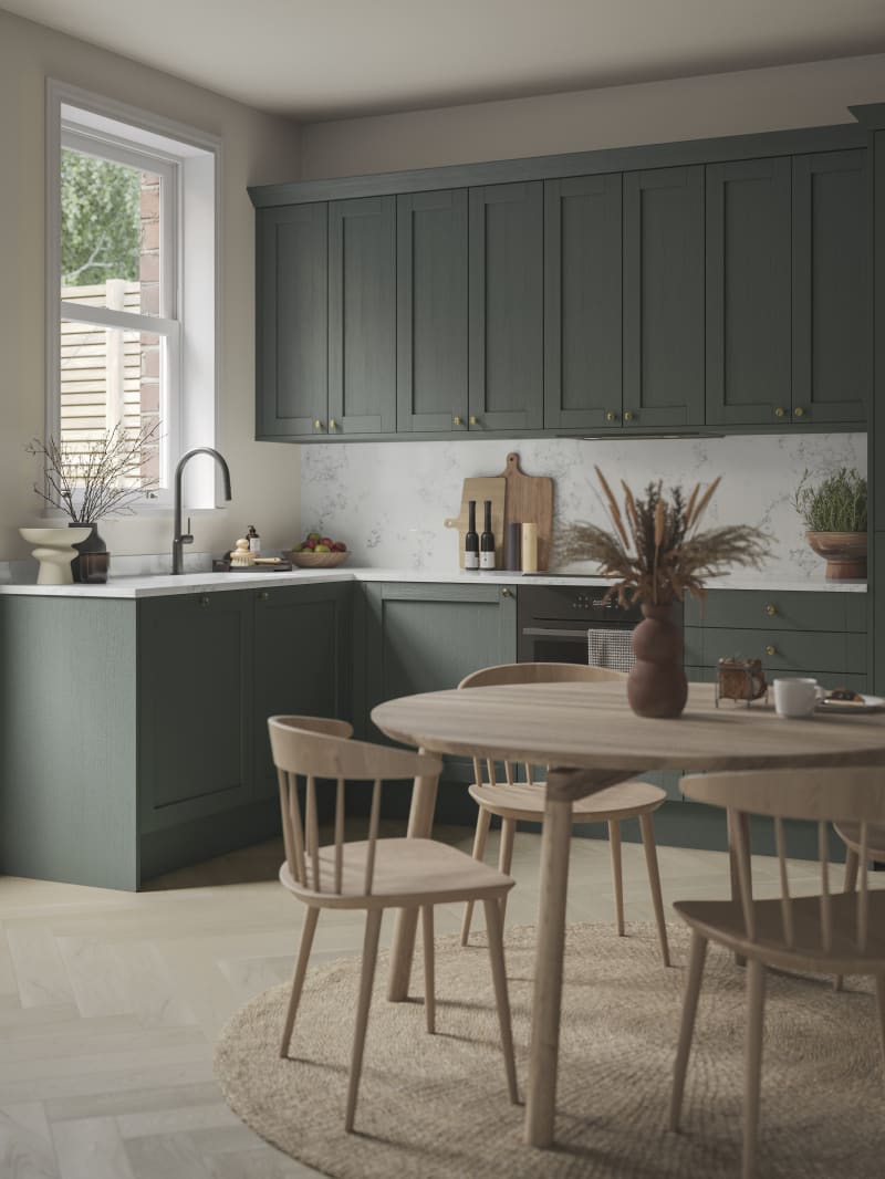 The Ambleside Shaker kitchen in a dark green, seen with a wooden dining table.