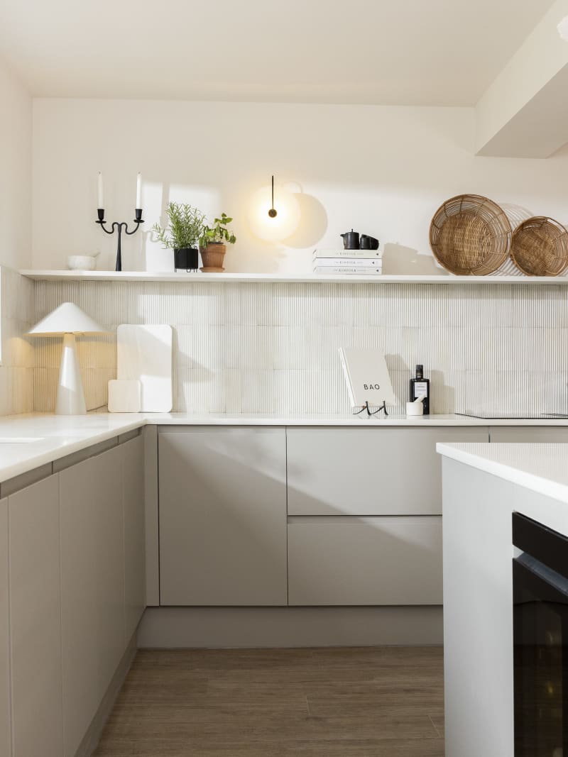 View of Yasmin Wyatt's open, light and airy neutral shade handleless Luna kitchen from Magnet, a white Corian worktop in Onyx, wine fridge integrated into kitchen island.