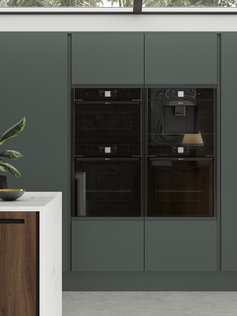 Black appliances integrated into full-height door units from Magnet's Duxbury range, seen in a rich dark green.